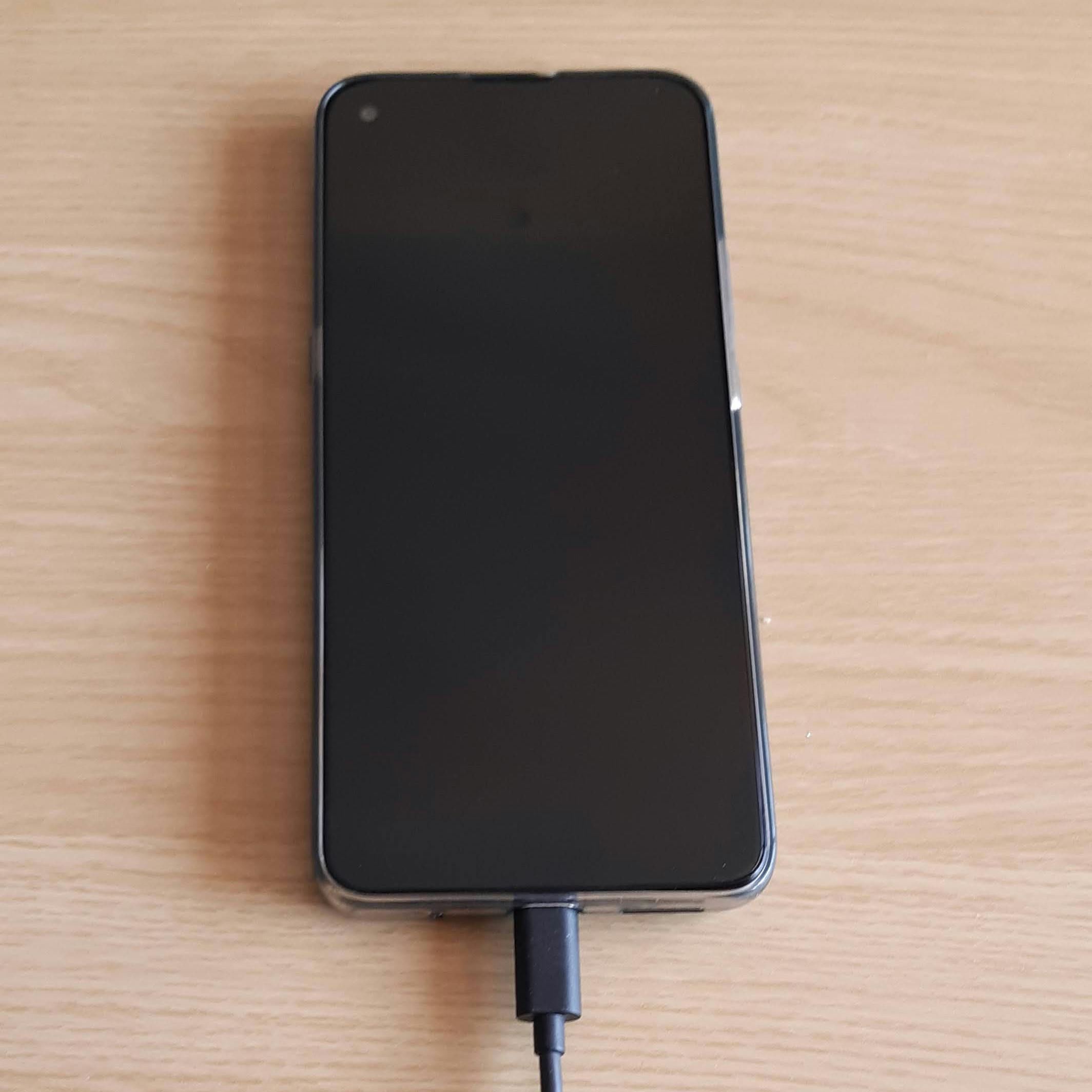 A smartphone with charging cable plugged in on a table