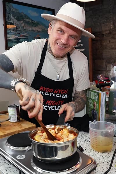 Matt stirring a saucepan filled with vegetables on a hob