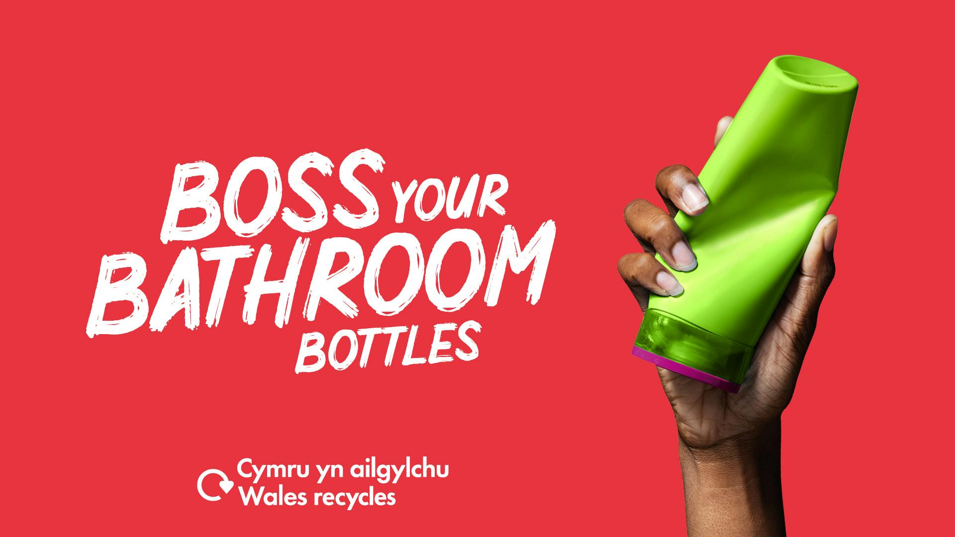 Woman's hand holding a green plastic shampoo bottle with the slogan "Boss your bathroom bottles"