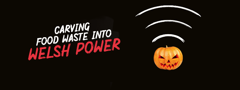 Black background with a pumpkin to the right that has white doodled waves coming out of the top. To the left is bold white and red text: "CARVING FOOD WASTE INTO WELSH POWER" Below smaller bold white text: "Recycling 1 pumpkin shell creates enough energy to power your home for 1 hour!" At the bottom is the white Wales Recycles logo and swoosh with a green Climate Action Wales logo next to it.